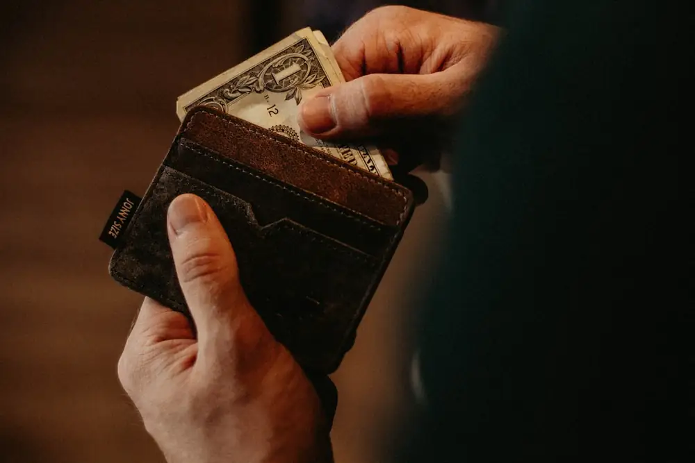 Dompet kulit dengan uang kertas di atas meja kayu